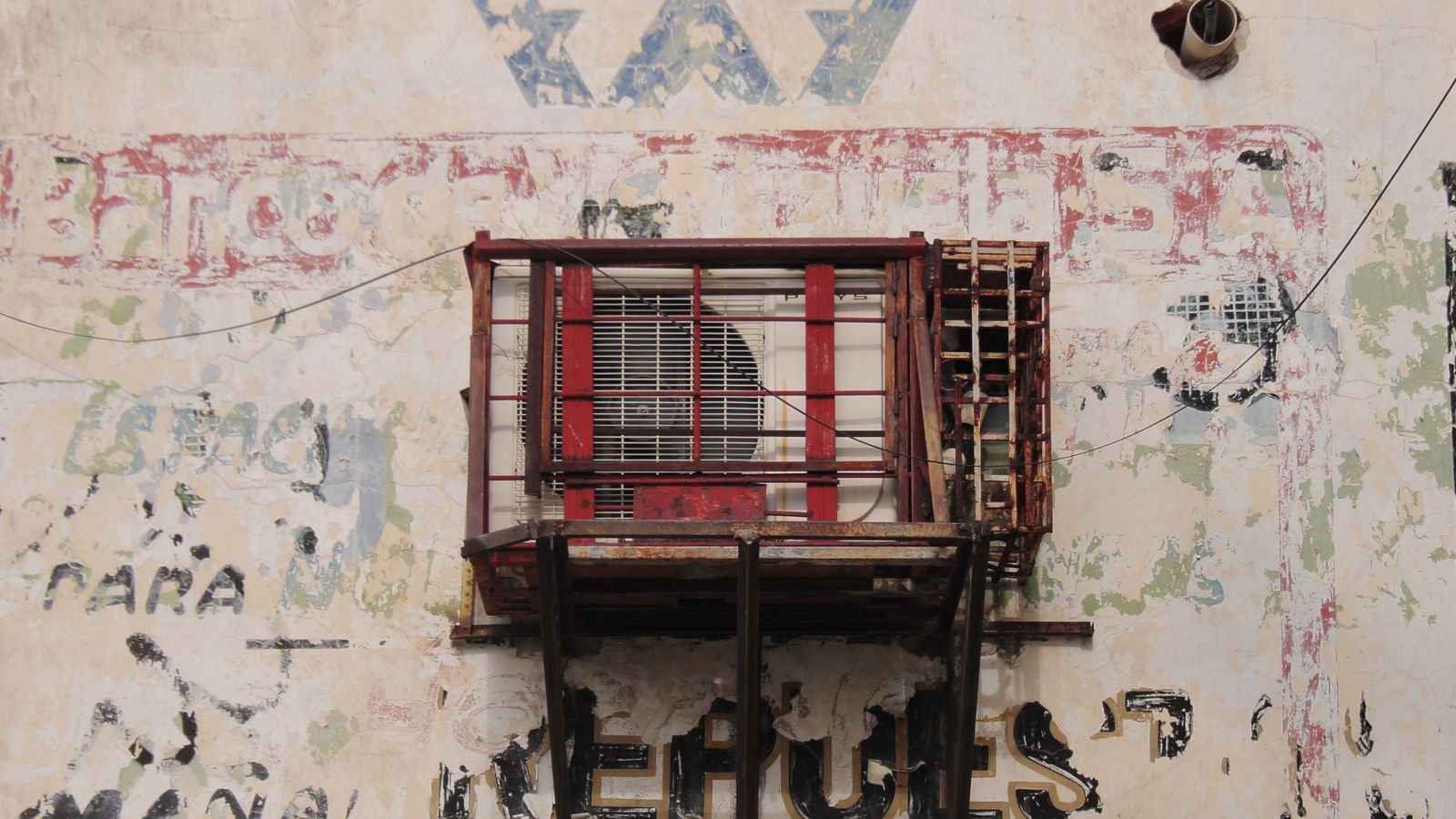 Weathered wall with air conditioner in Maracaibo, showcasing urban decay and street art.