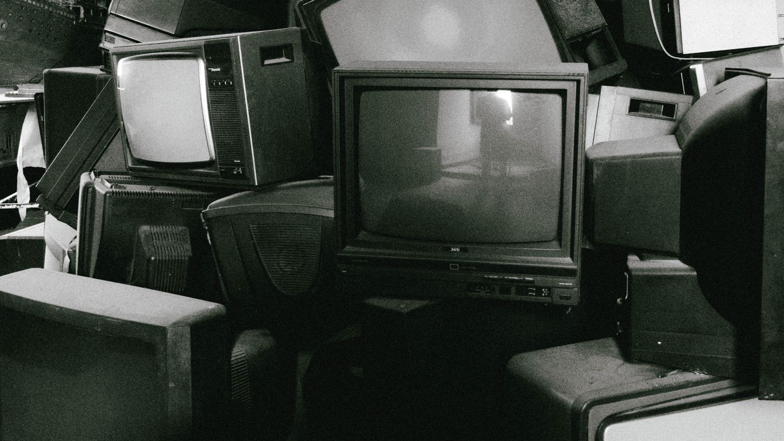 A stack of retro televisions evokes nostalgia and past technology in black and white.