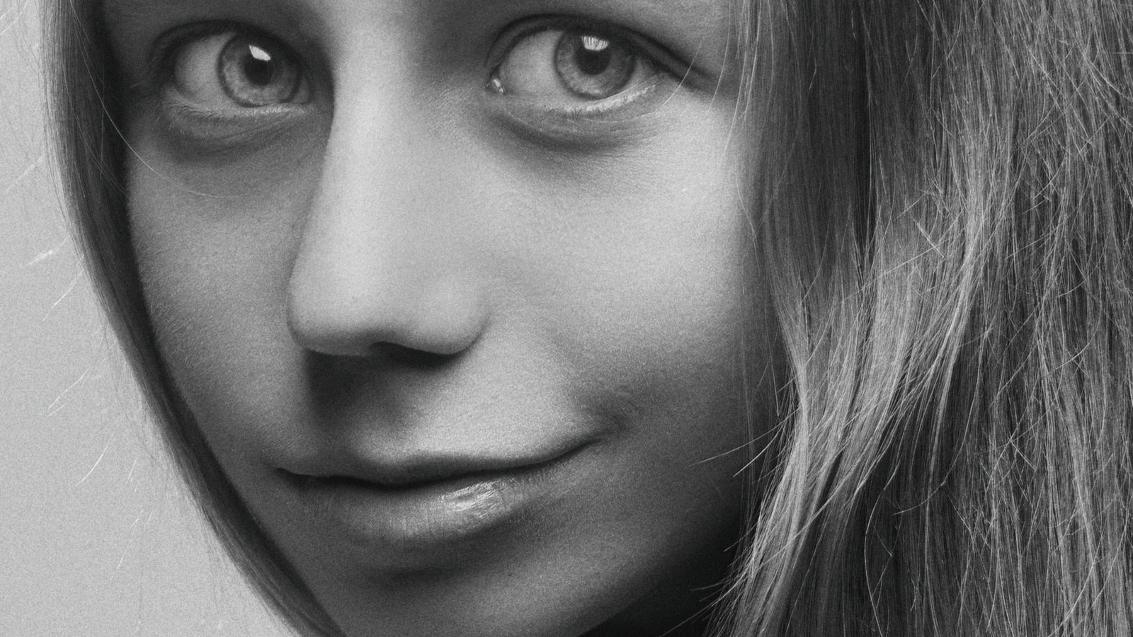 Close-up black and white portrait of a smiling young woman with expressive eyes.
