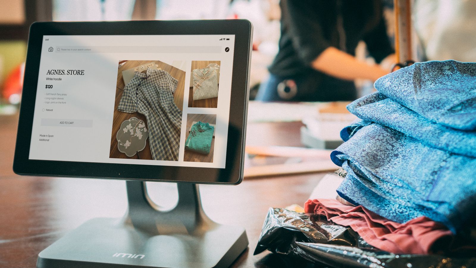 A digital point-of-sale system in a small fashion boutique with clothes displayed on a tablet.