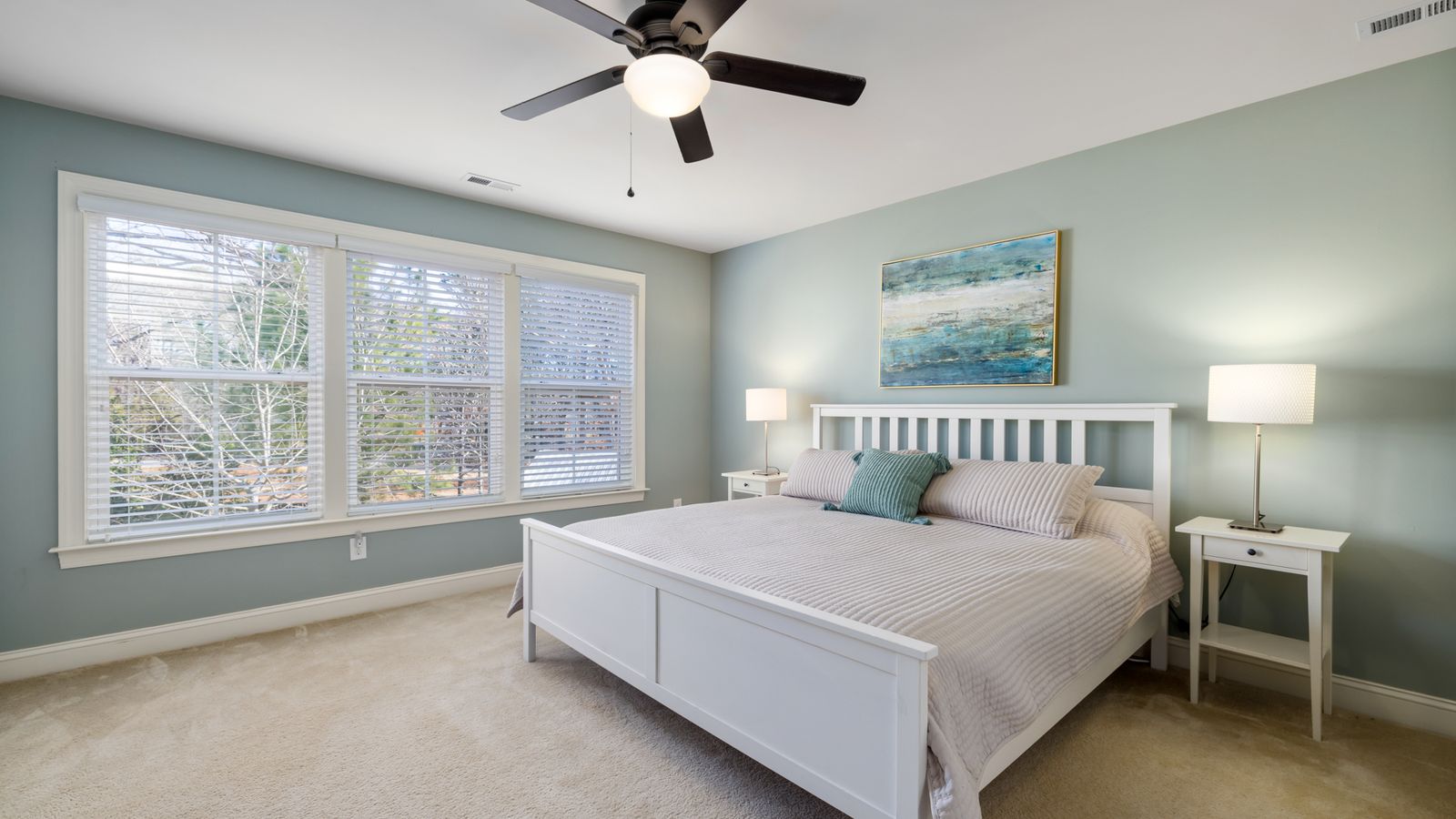 Bright modern bedroom featuring a comfortable bed, large windows, and stylish decor.