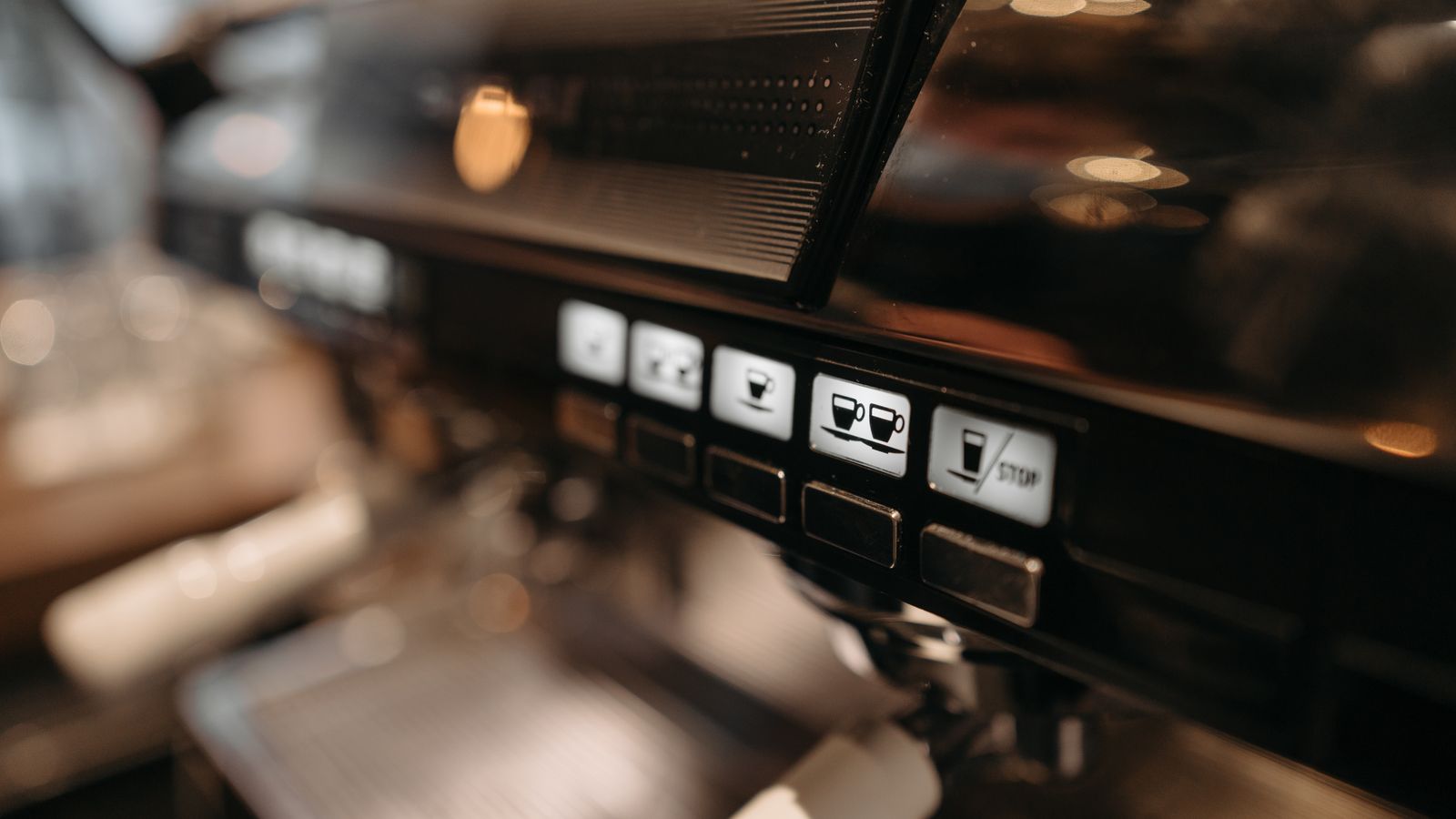 Detailed view of espresso machine panel in a cafe setting, highlighting coffee brewing controls.