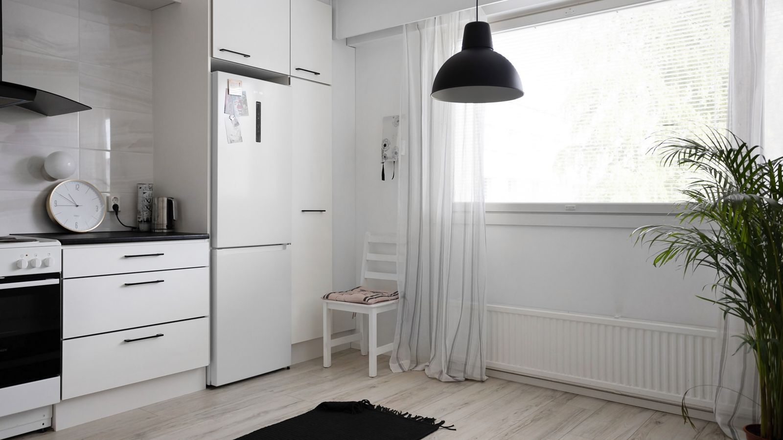 A sleek, minimalist kitchen featuring white cabinets, large window, and modern decor for a bright interior design.