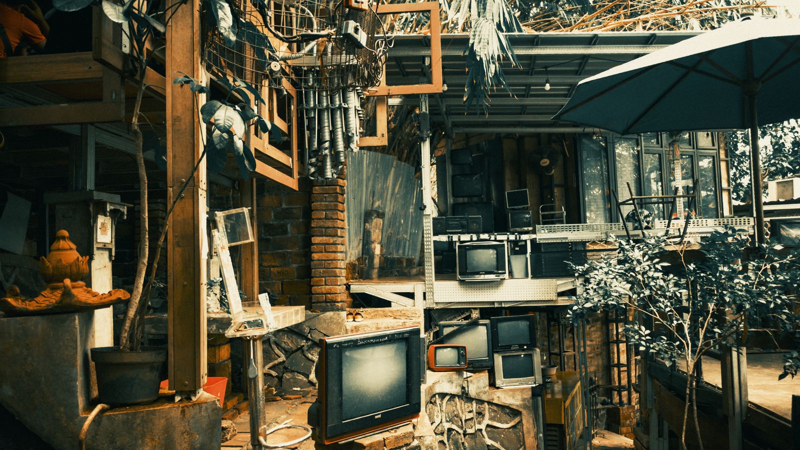 A rustic outdoor area in Banten, Indonesia, featuring vintage TVs and eclectic decor.