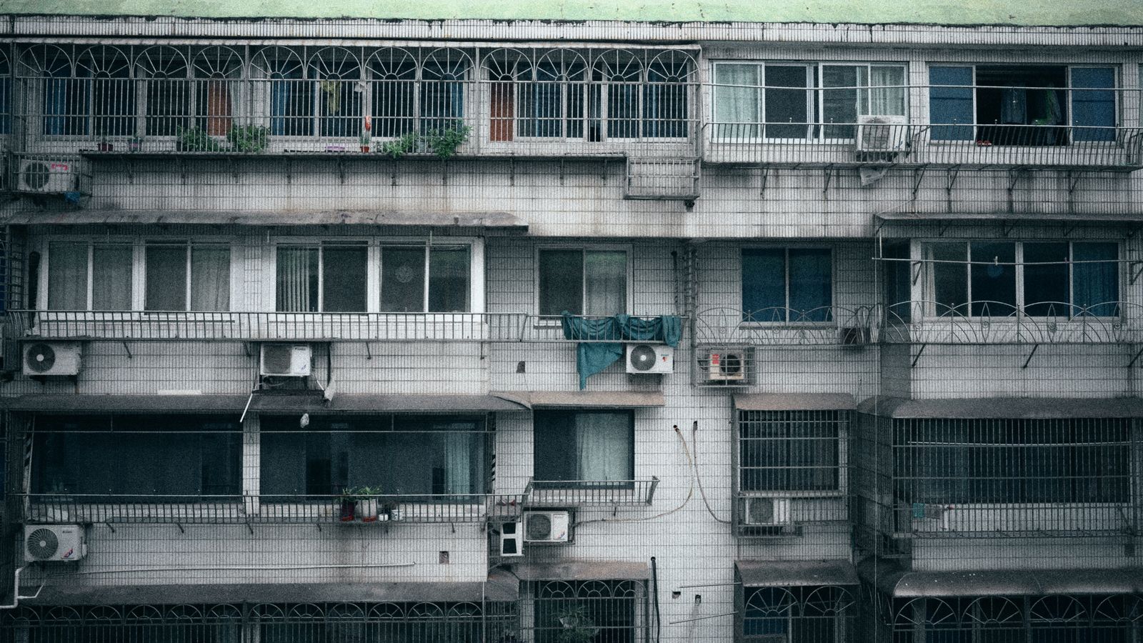Facade of a multi-story apartment building with air conditioning units visible on each floor.