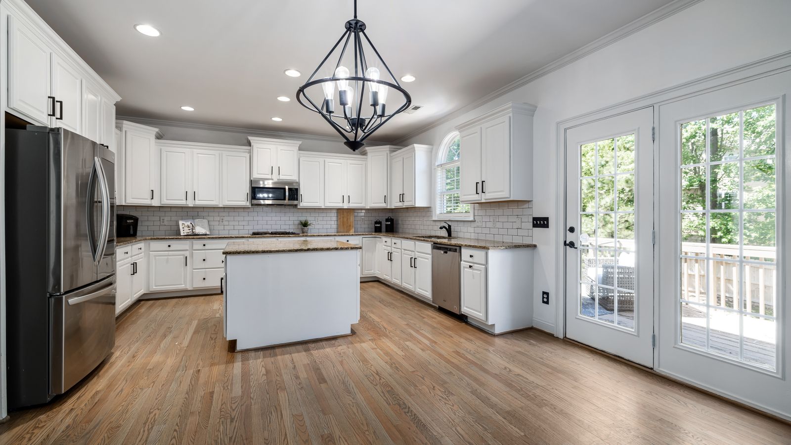 Bright, contemporary kitchen featuring sleek white cabinetry and a central island with ample natural light.
