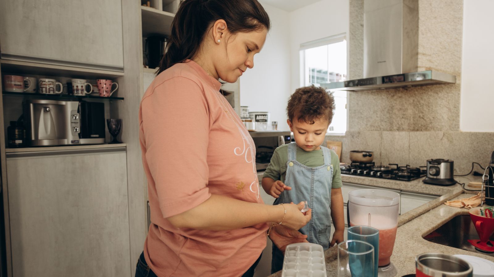 A woman and child making a smoothie in a modern kitchen, emphasizing family bonding.