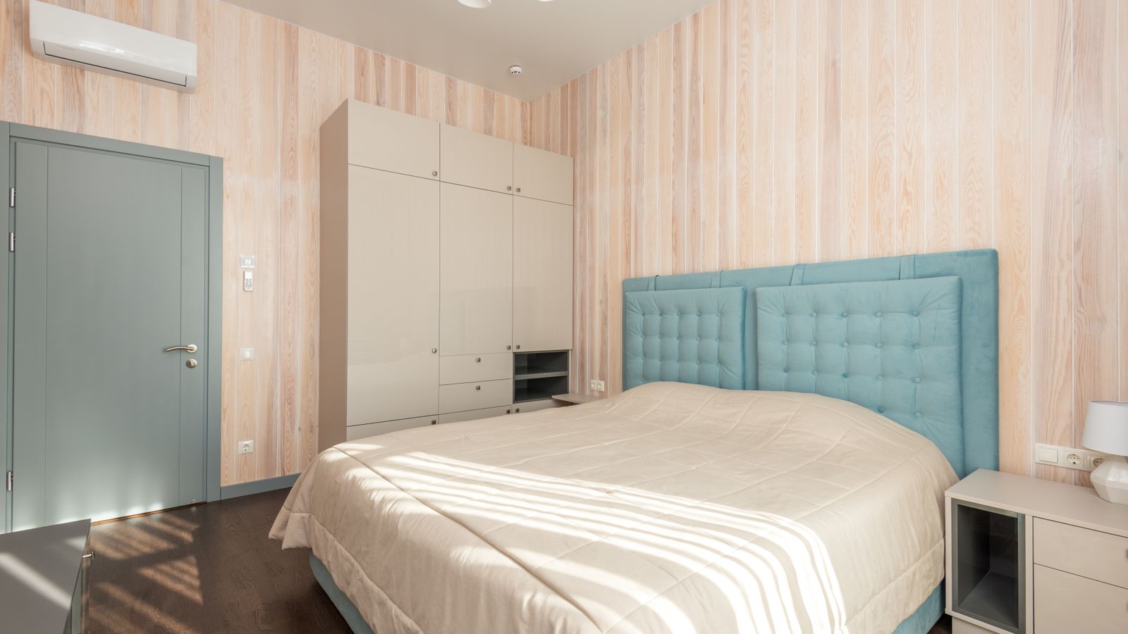 Spacious bedroom with teal accents and modern furnishings for a cozy atmosphere.