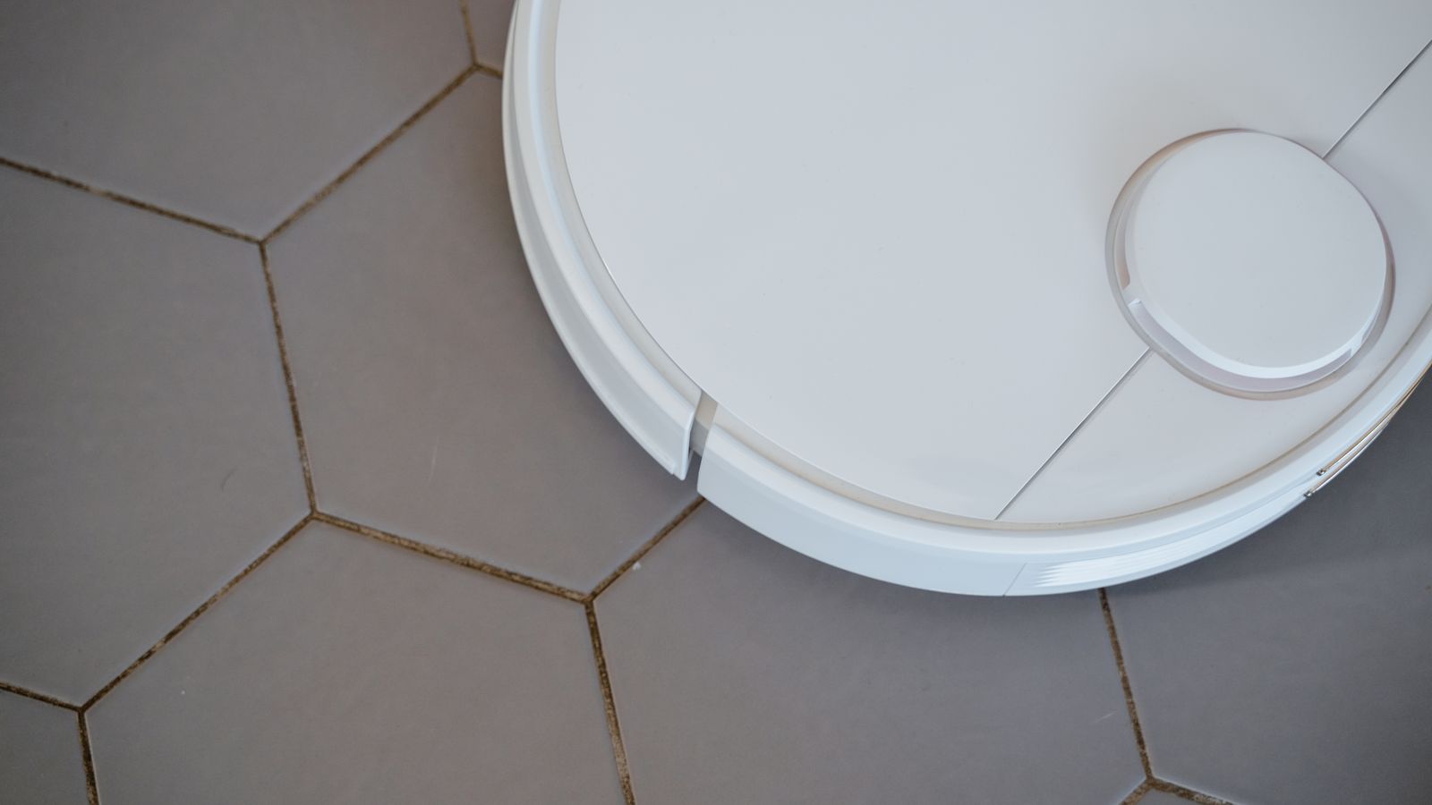 Close-up of a robotic vacuum cleaner on hexagonal tiles for efficient cleaning.