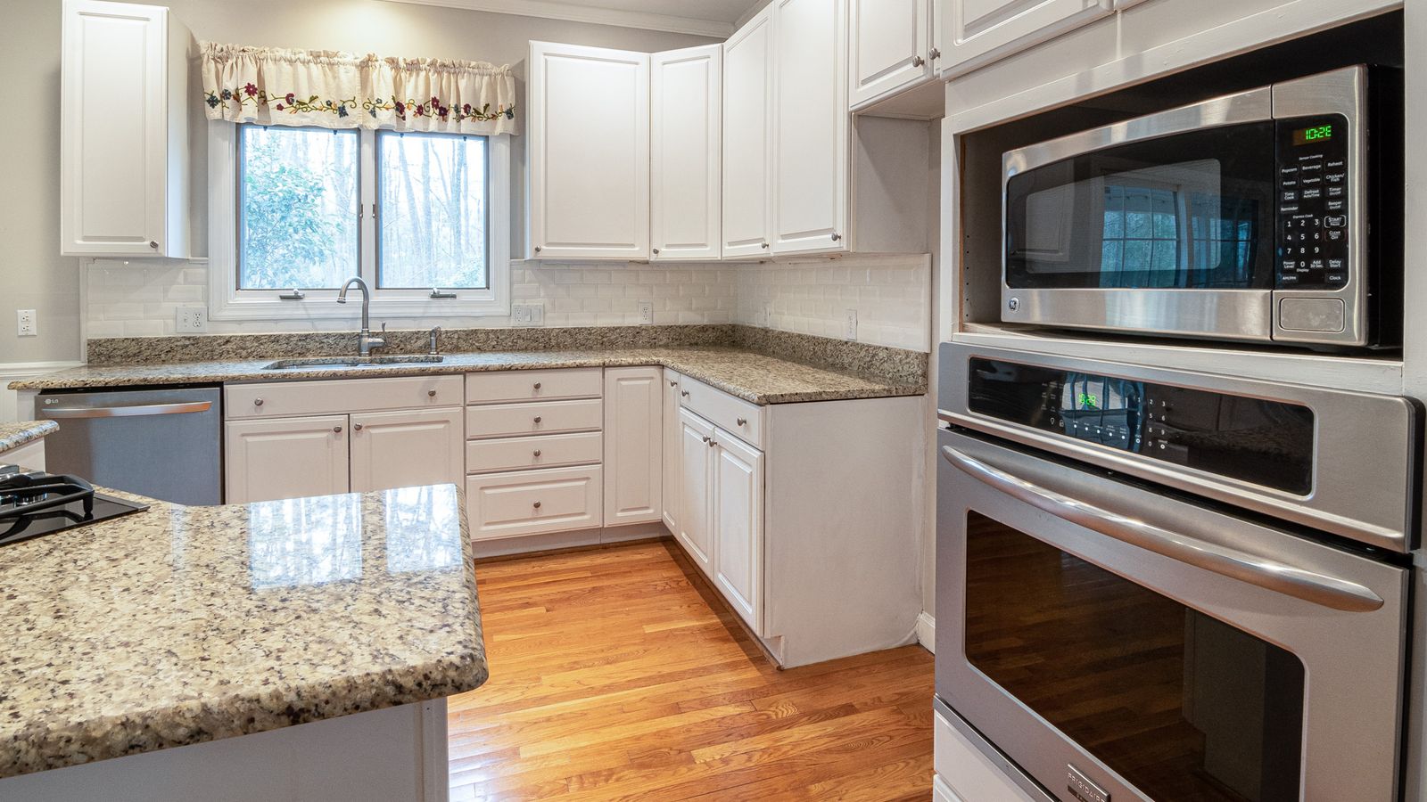 Spacious modern kitchen with white cabinets and granite countertops.