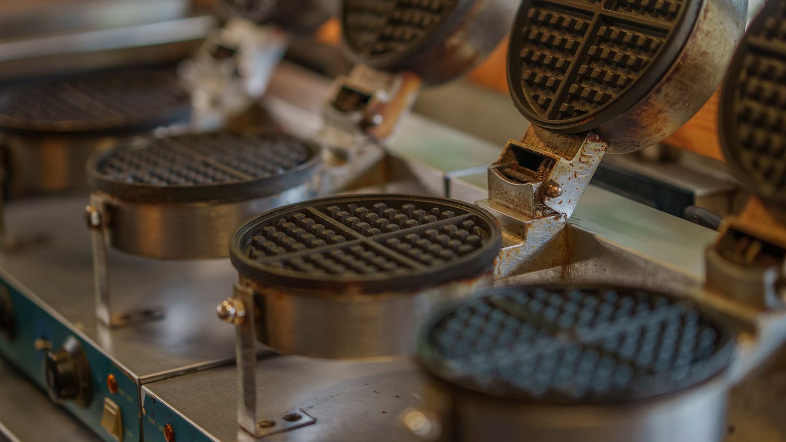 Close-up of multiple waffle makers in a commercial kitchen setting.