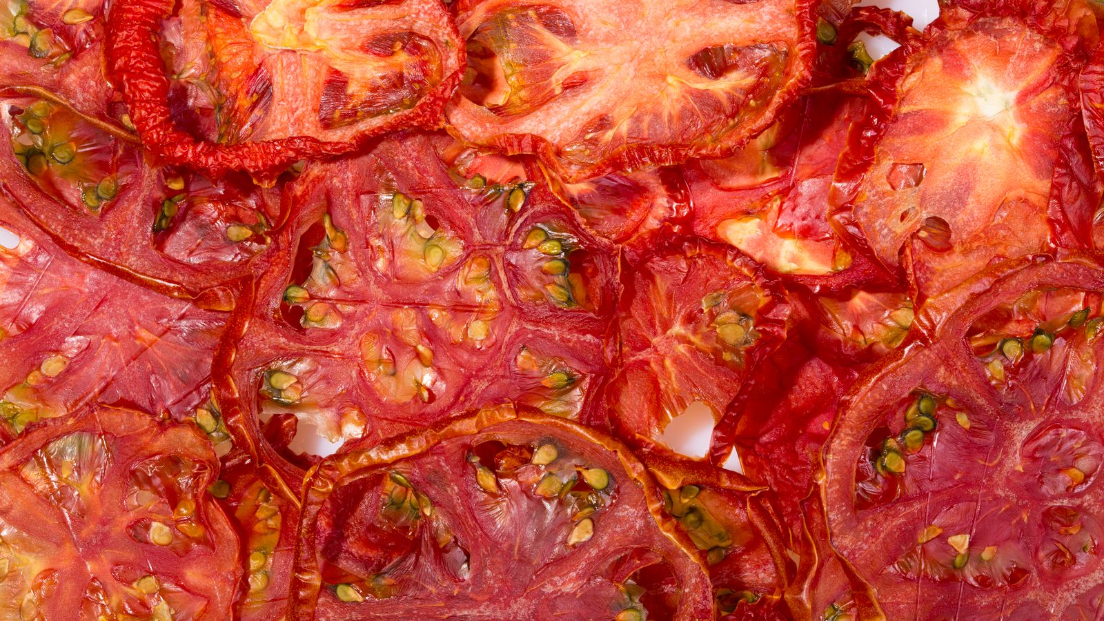 Close-up view of vibrant red dried tomato slices, ideal for backgrounds or culinary content.