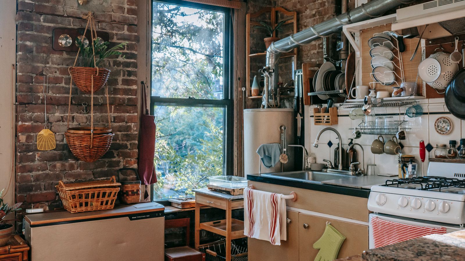 Charming rustic kitchen featuring wooden decor, exposed brick, and appliances with a sunlit window view.