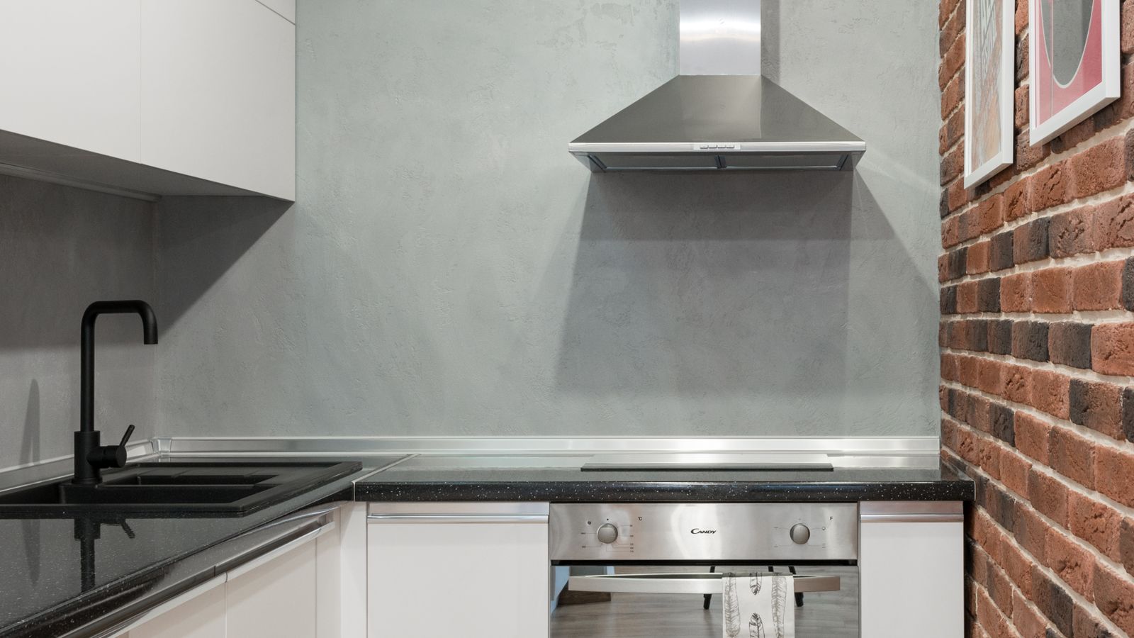 Contemporary kitchen interior with stainless steel appliances and brick wall.