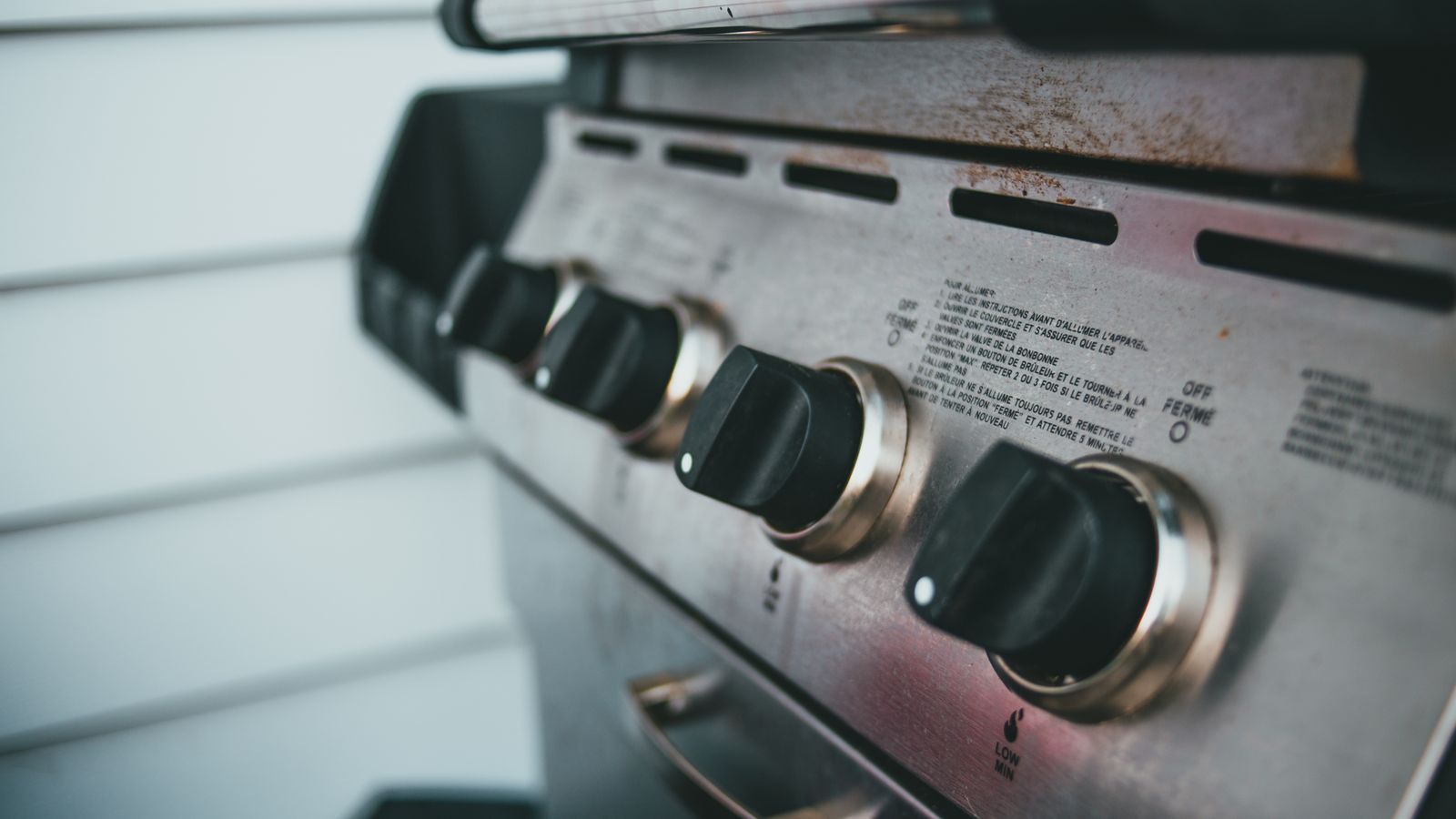 Detailed view of barbecue grill controls, showcasing knobs and stainless steel surface.