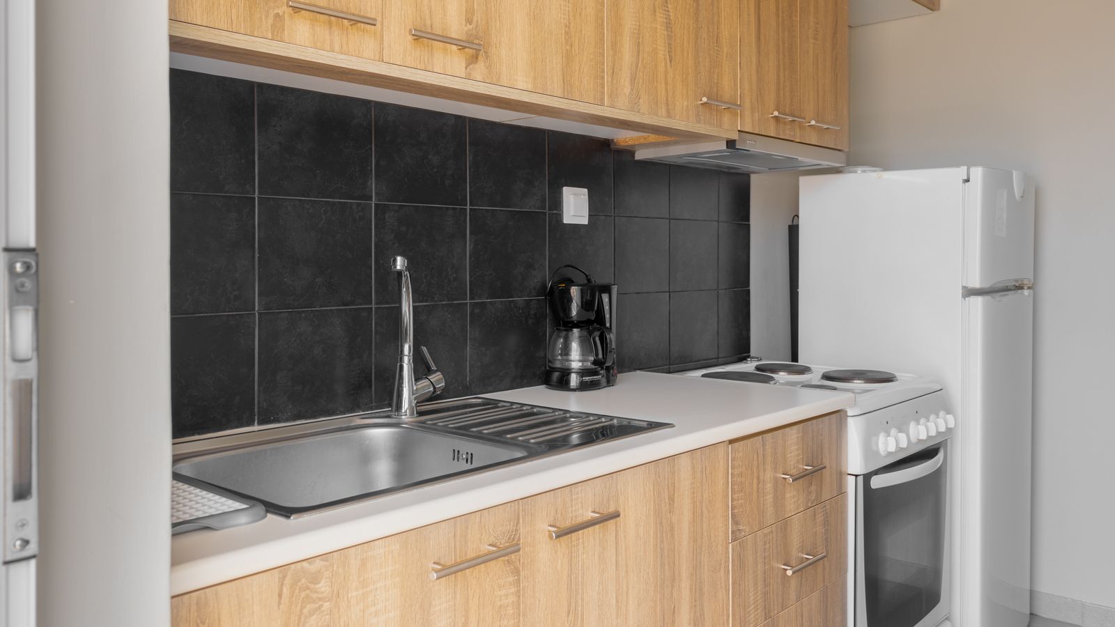 Sleek kitchen setup featuring wooden cabinets, sink, and appliances.