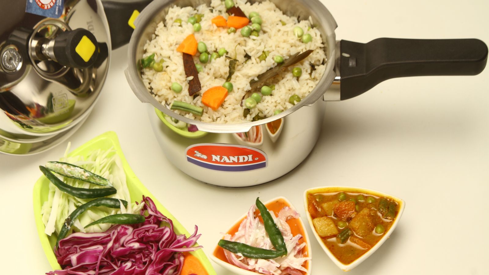Colorful Indian vegetable rice served with salads and curry, presented with a pressure cooker.