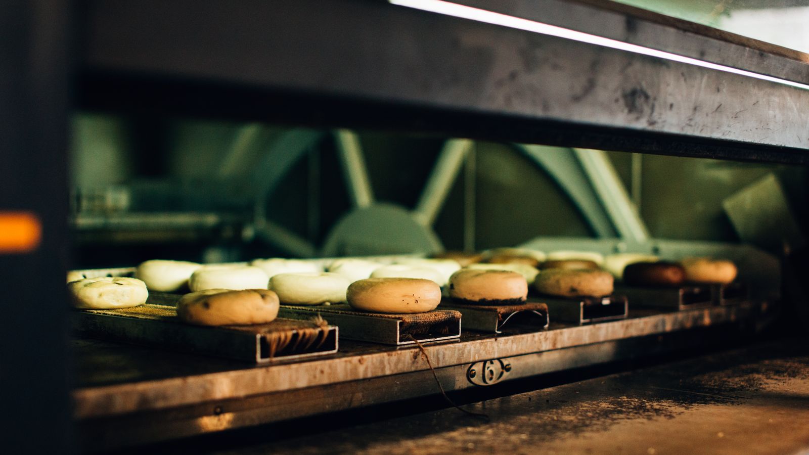 Multiple bagels baking in an industrial oven, showcasing a warm bakery ambiance.