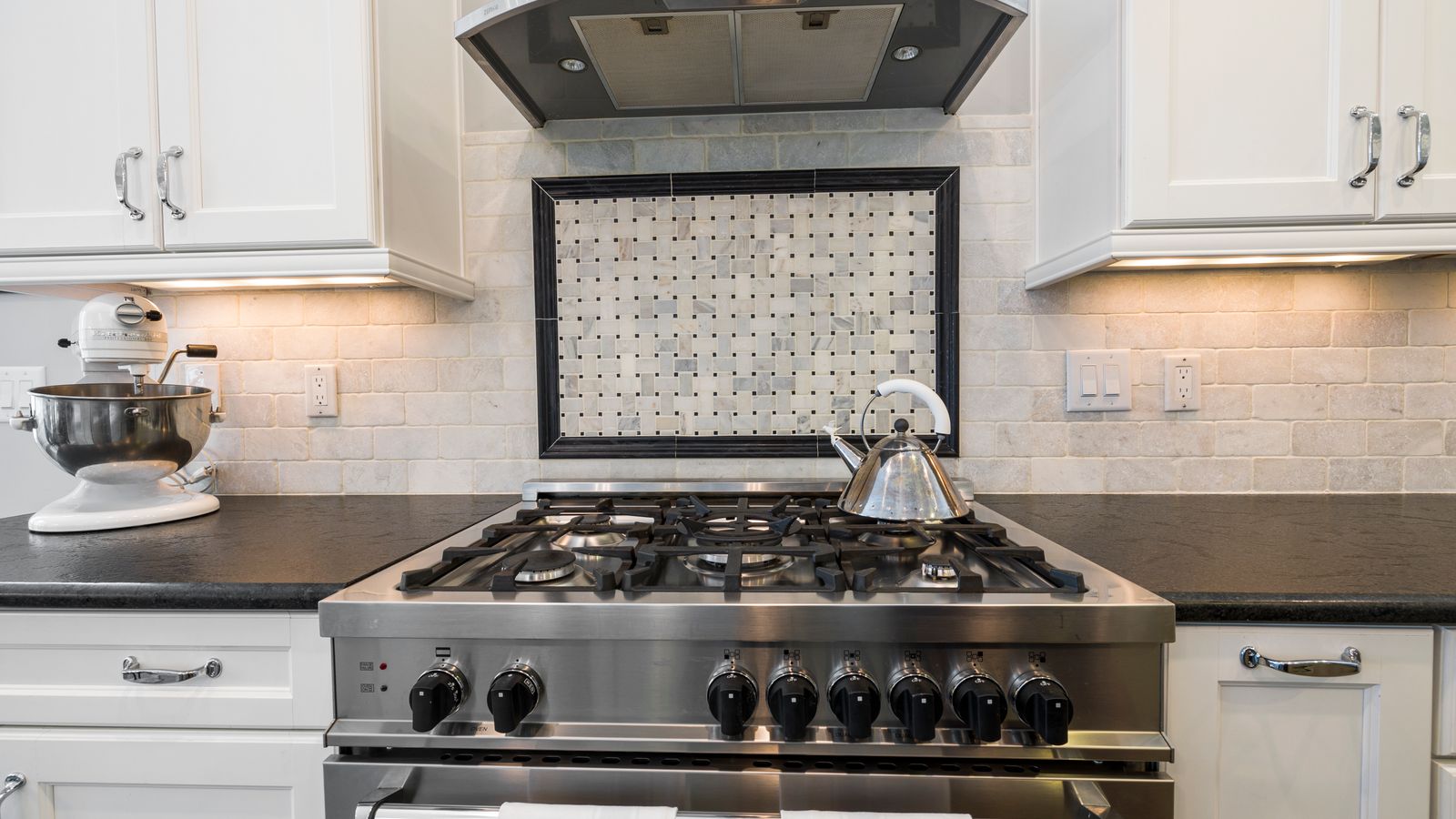 Contemporary kitchen featuring a stainless steel stove and kettle with sleek cabinetry.