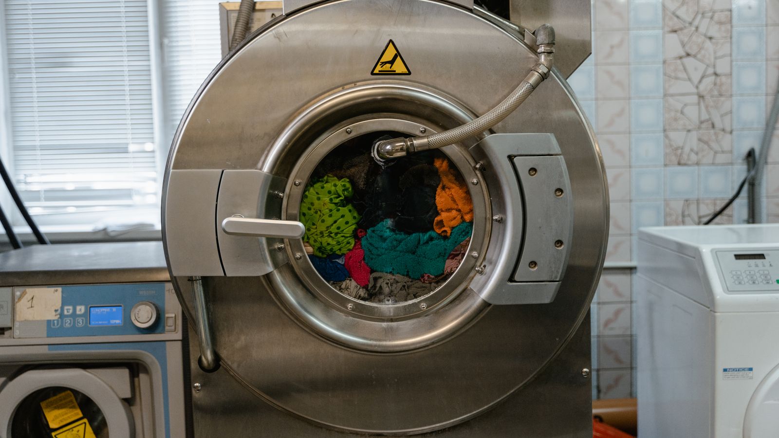 A close-up of an industrial washing machine operating in a laundry facility.