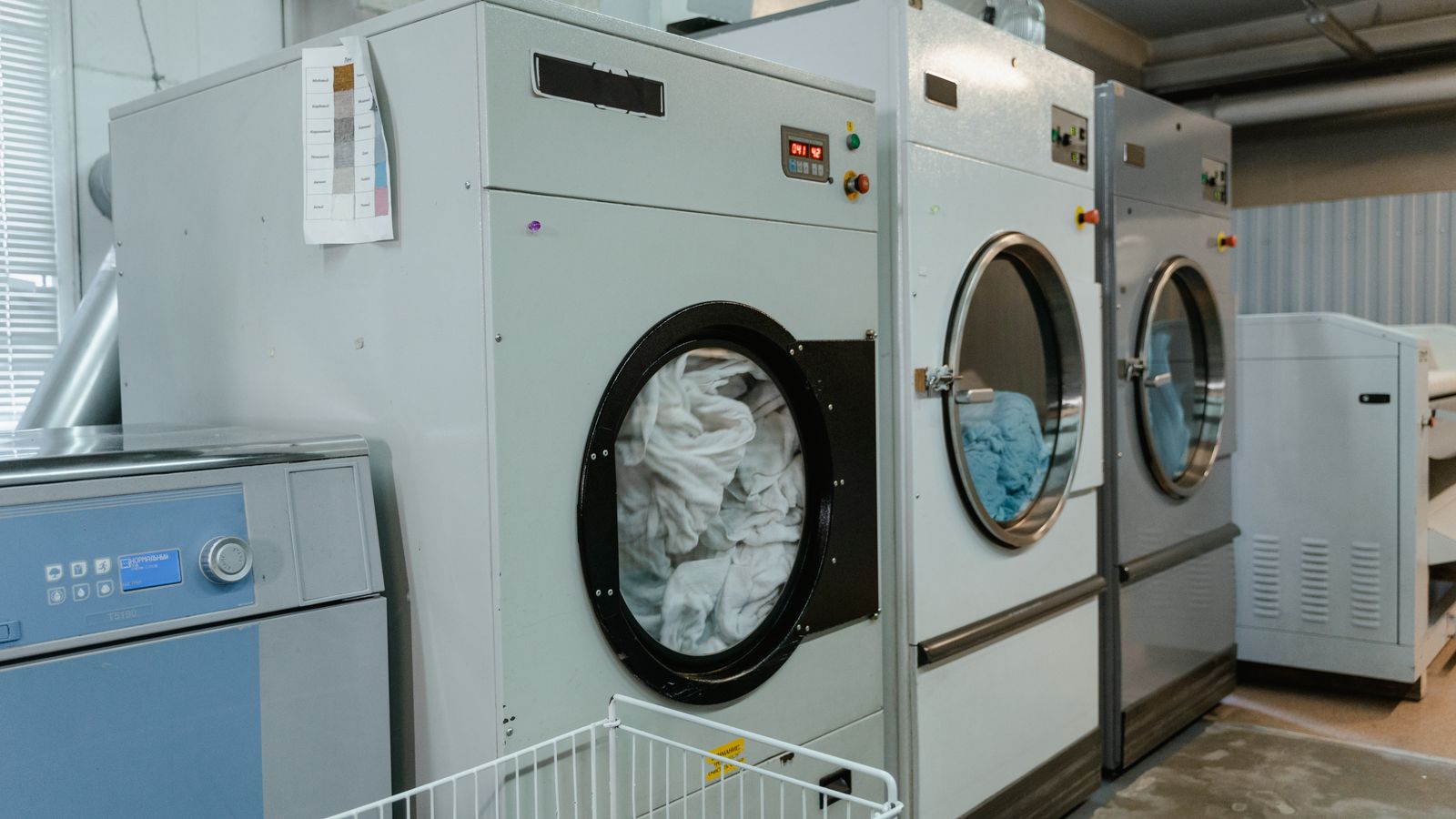 Interior view of industrial laundry machines in a facility with linens being washed.