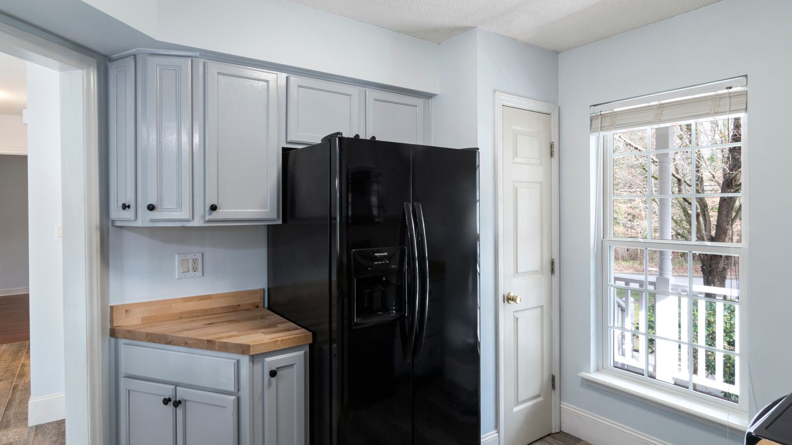 A modern kitchen featuring a sleek black refrigerator and large window.
