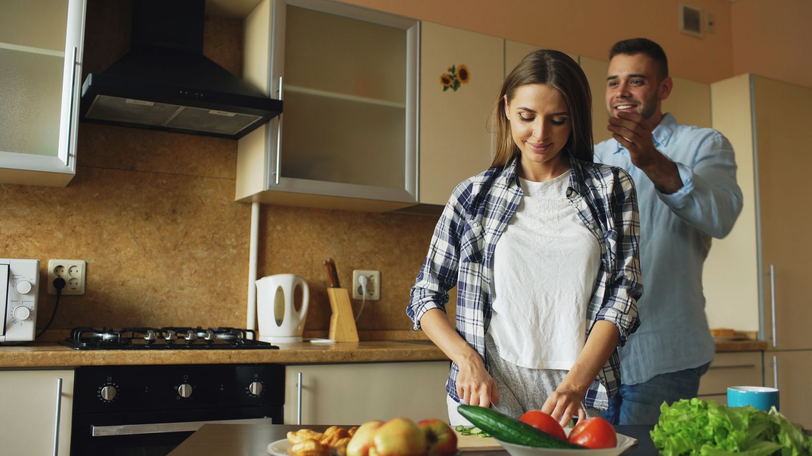 A cheerful couple enjoys preparing healthy meals together in a cozy kitchen setting.