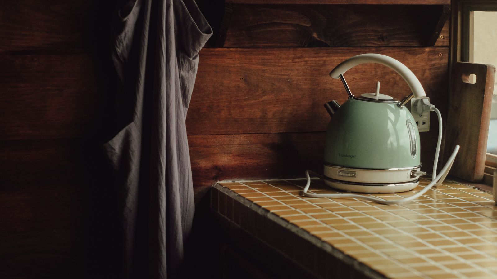 A cozy kitchen scene featuring a vintage teal kettle on a tiled counter with a warm, rustic feel.