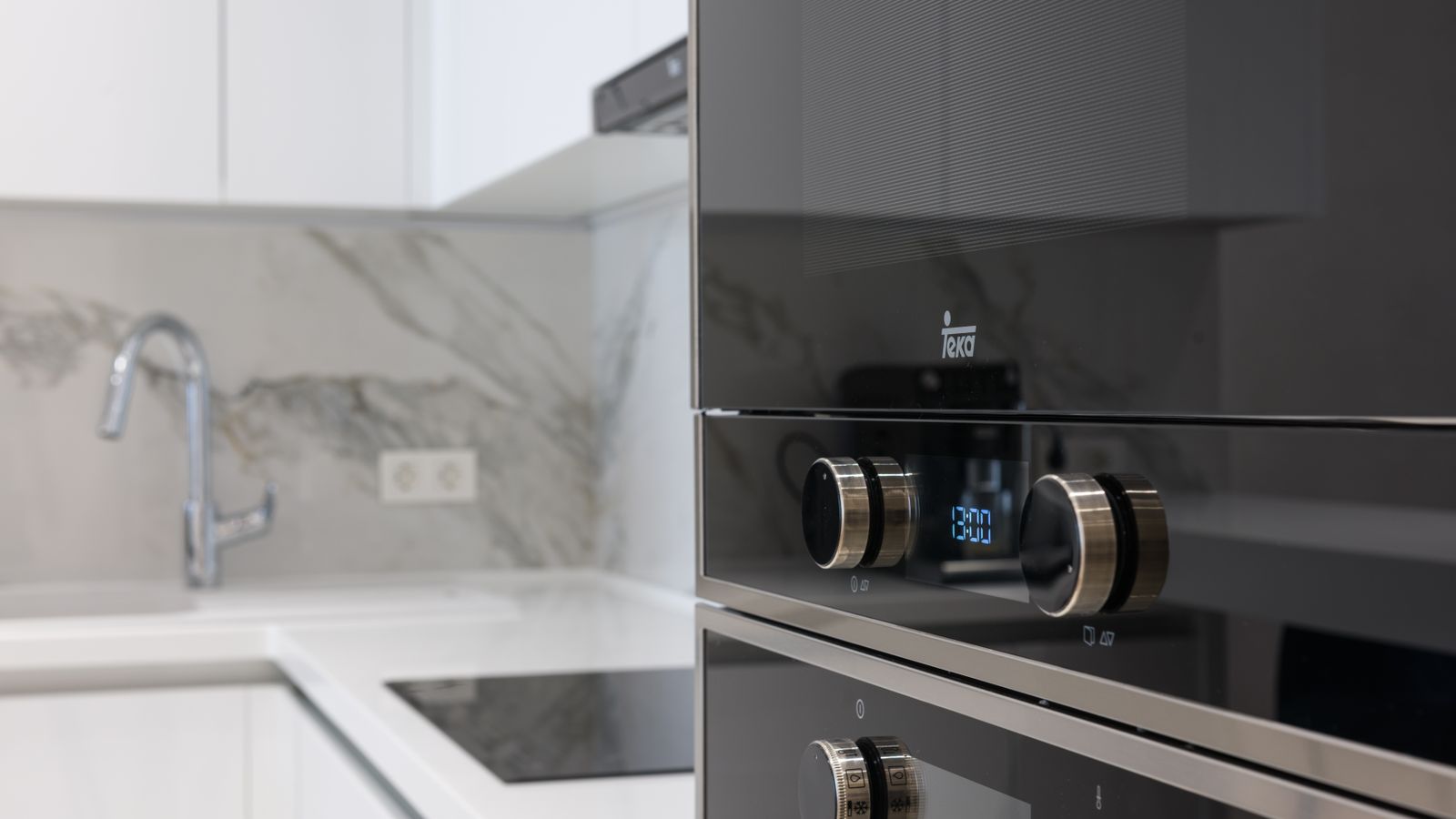 Interior of contemporary kitchen with stainless white surface induction cooker and electronic stove in modern apartment