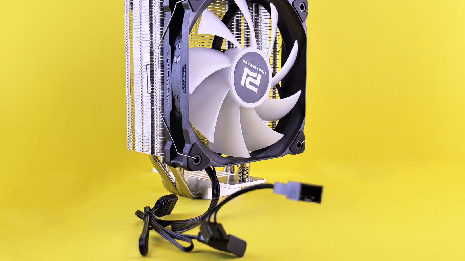 PC cooling fan with heatsink and cable against a bright yellow backdrop.