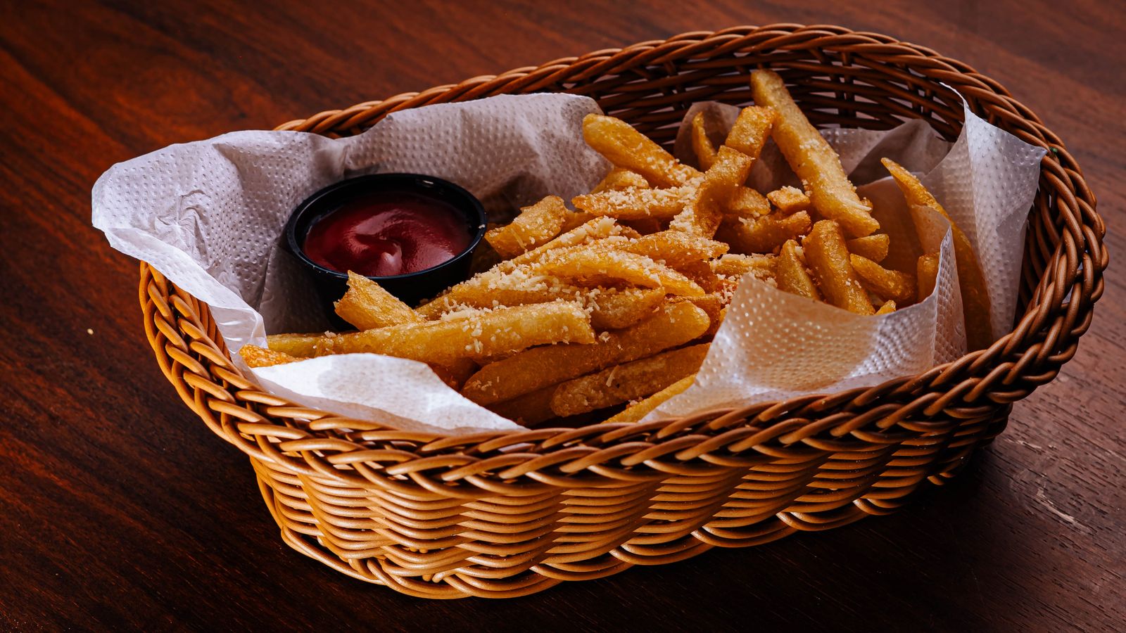 Delicious French fries with parmesan served in a basket with ketchup dip.