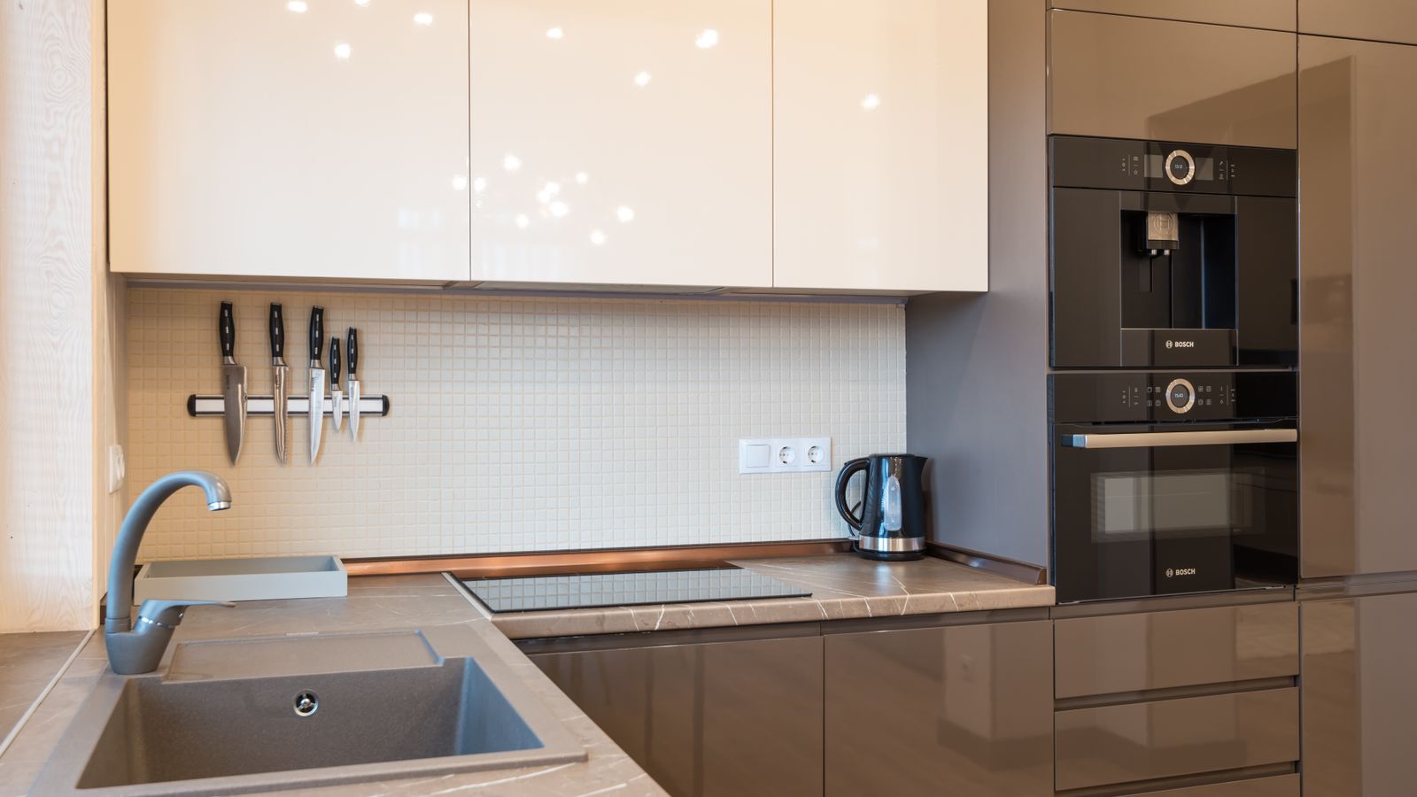 Interior of kitchen with minimalist glossy furniture and modern appliances in light contemporary apartment
