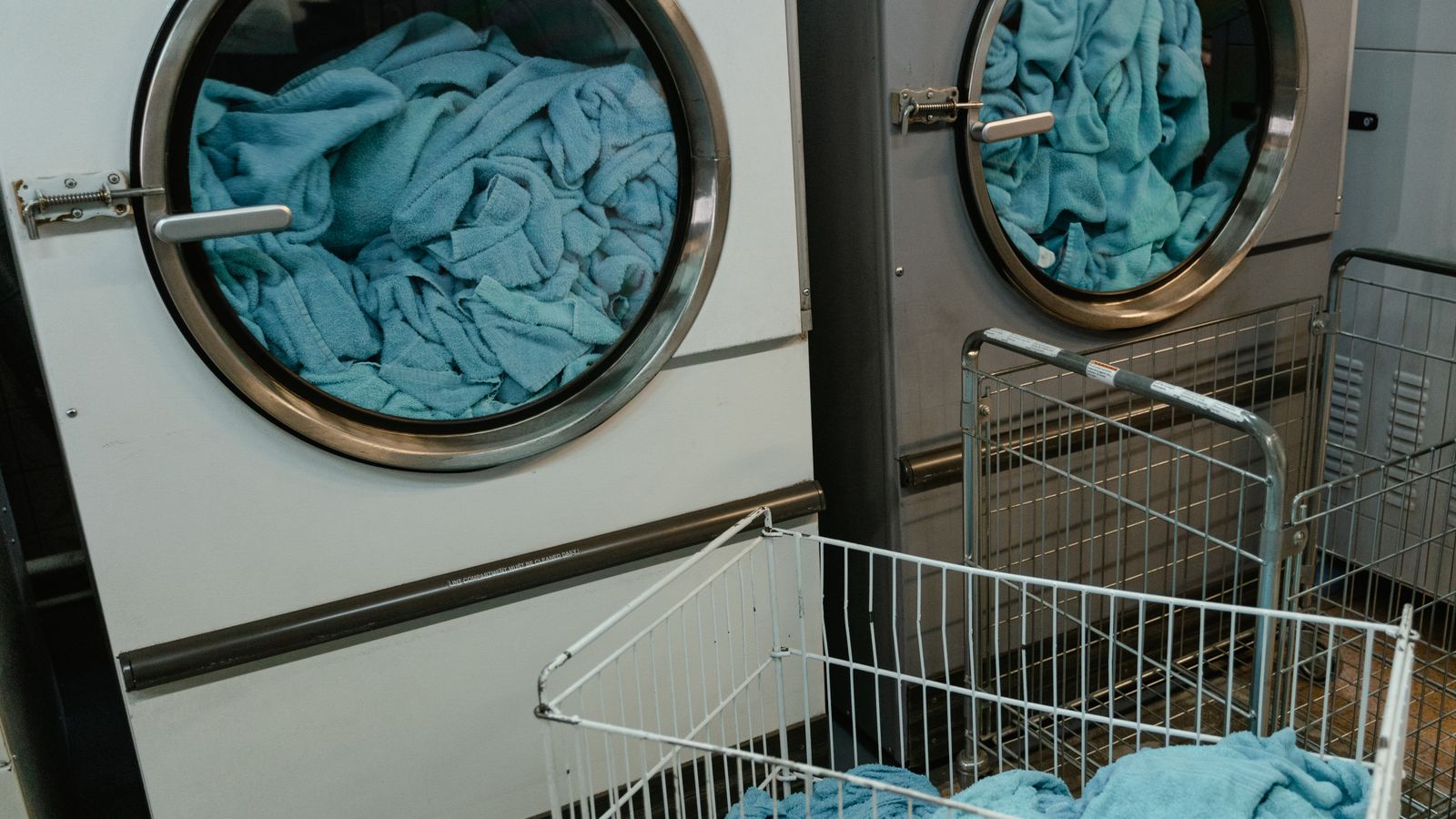 Industrial washing machines with blue towels in a laundry facility.