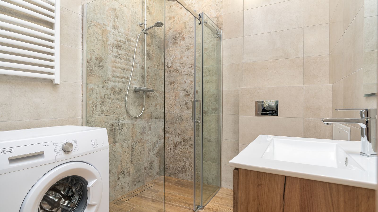 Sleek bathroom with a glass shower enclosure, a washing machine, and a contemporary sink.