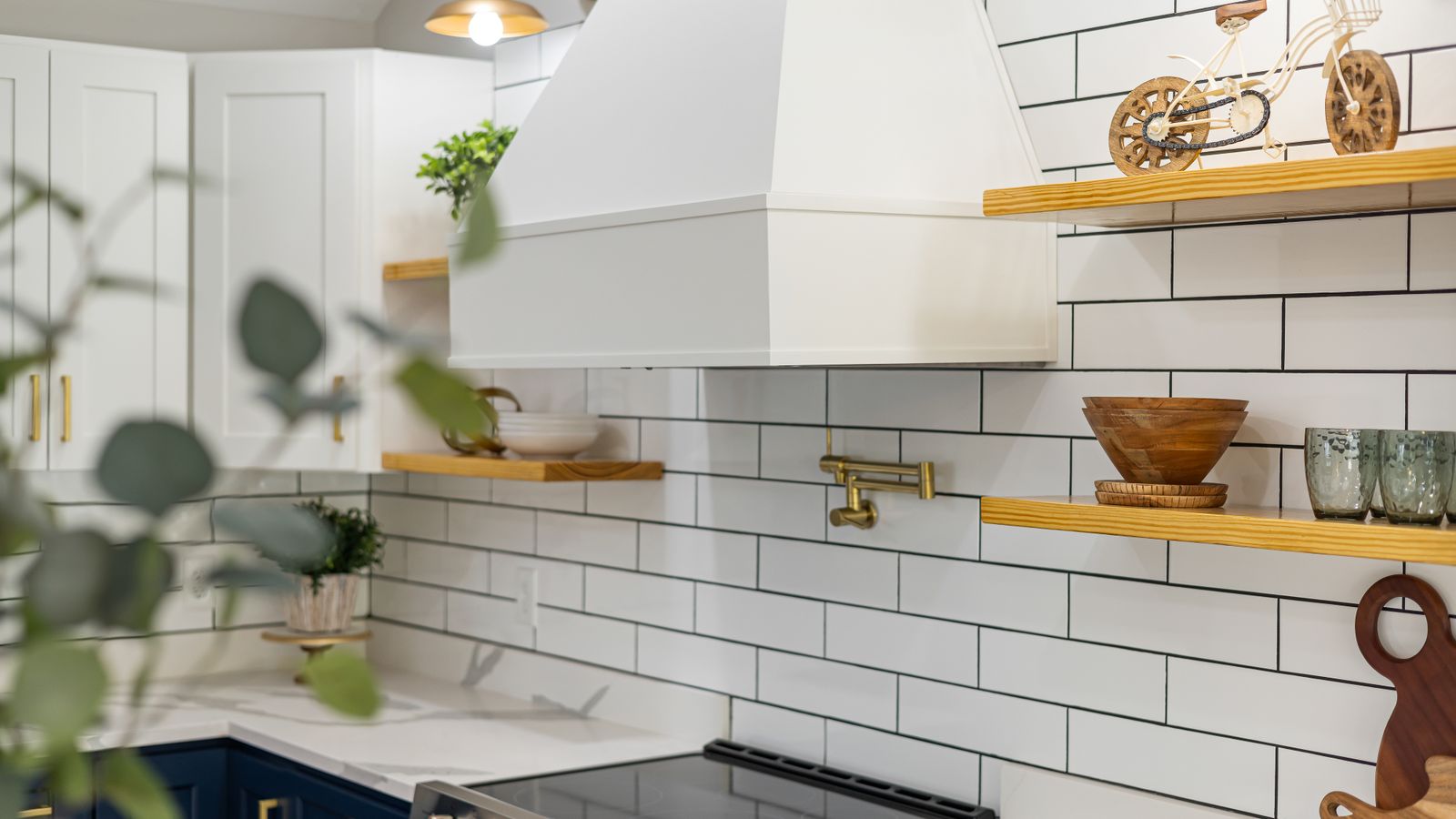 Chic kitchen with white cabinets, subway tiles, and wooden shelves.