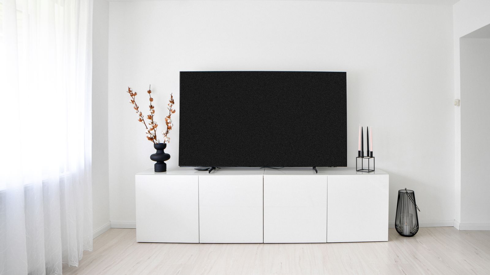 A sleek and minimalist Scandinavian living room with white decor and electronics.