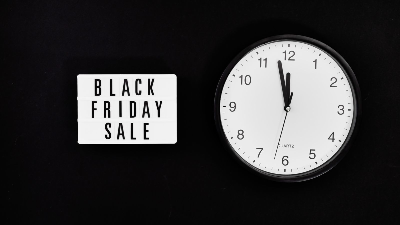 Minimalist clock with a Black Friday sale sign on black background, highlighting a midnight sale countdown.